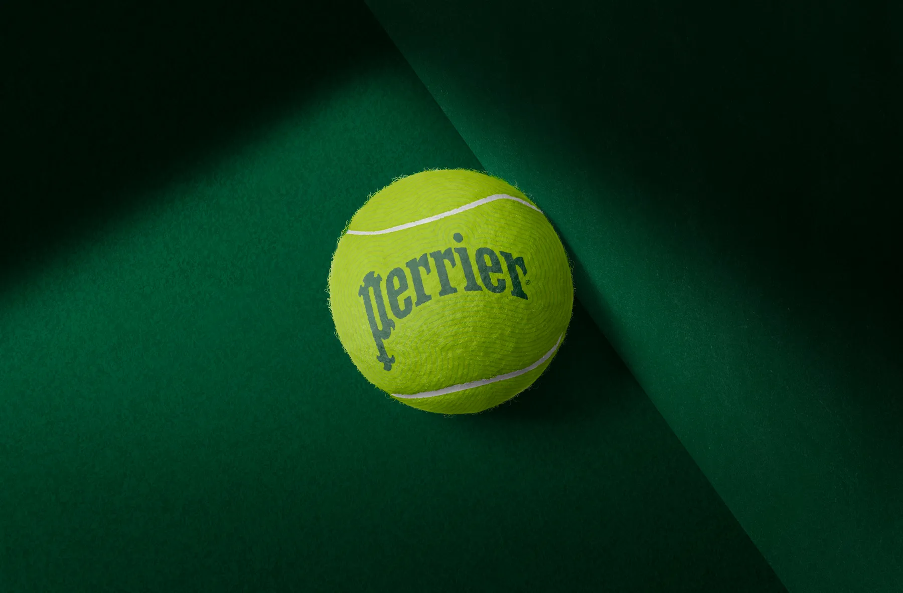 A tennis ball printed with the Perrier logo, product mockup